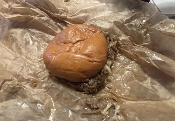 A brown Philly Cheesesteak is served with cheese, bell pepper, onions, and steak. The Philly Cheesesteak burger is served with a brown wrapper