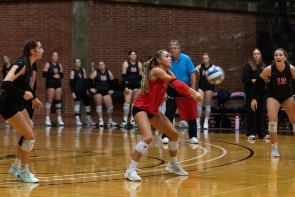 Kiana Merrill (#3) is slightly squatted with her arms out in front of her, ready to pass the incoming ball.
