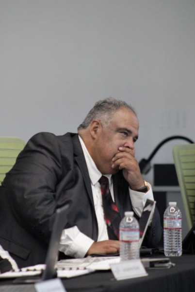 El miembro del Consejo de Administración se inclinó para taparse la boca durante los informes de los constituyentes en la reunión del 10 de septiembre de 2025.