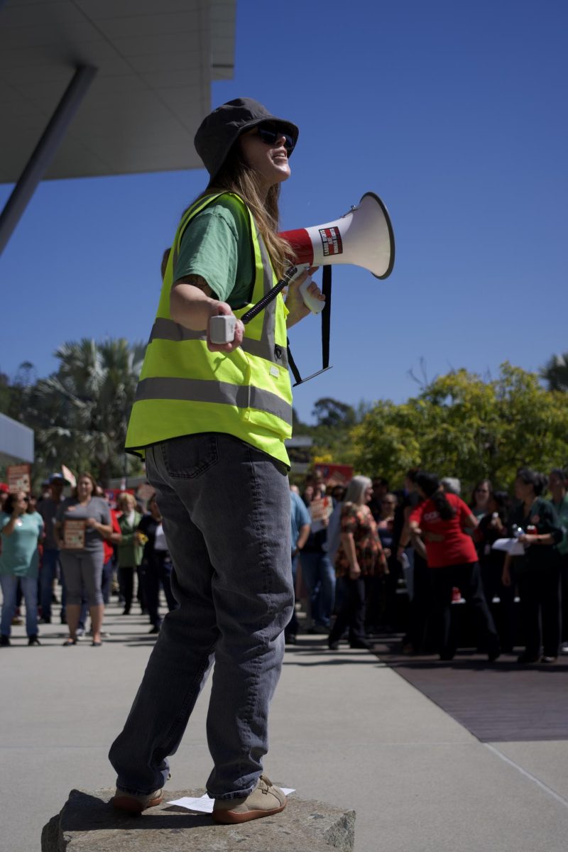 Jena Kruhmin, vicepresidenta de CCE, dirige a la multitud en un canto durante la manifestación de CCE frente a la Biblioteca del Colegio Palomar el 7 de octubre de 2025.