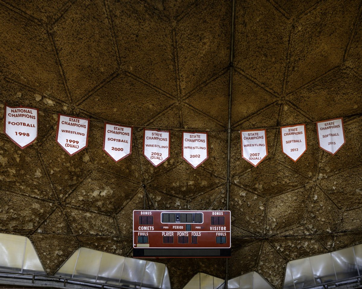 Close-up of red and white championship banners hanging in a row over a red scoreboard, with the Dome’s rough, brown ceiling panels filling the background.