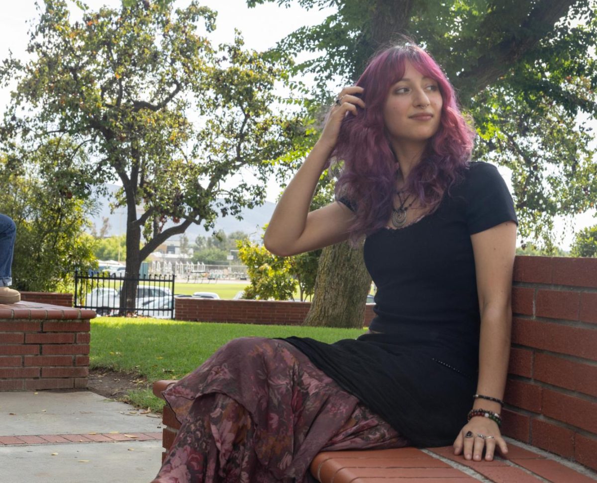 Mia Cherabie poses on a benchunder the clock tower.