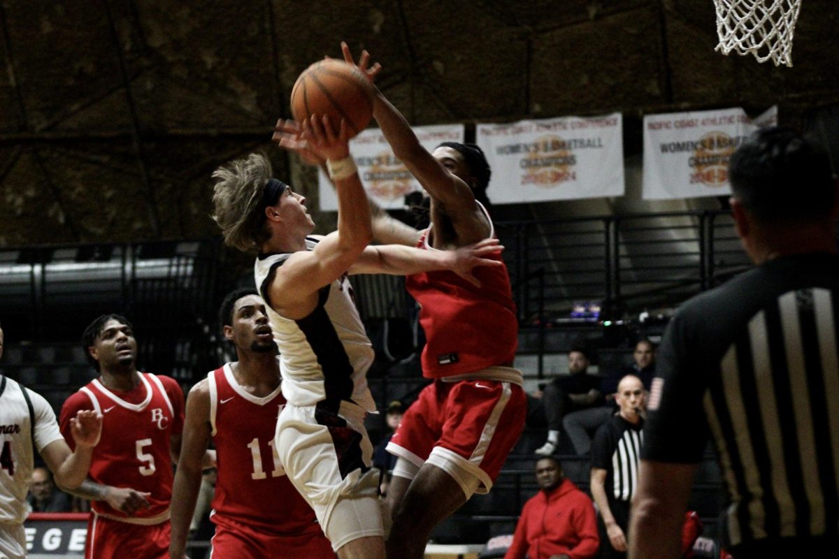 Benjie Nudo (#0) is trying to shoot the basketball as a Bakersfield player has his arms up, blocking the shot.