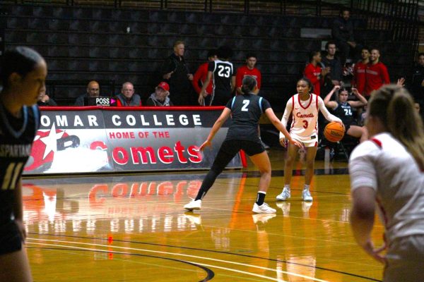 Palomar basketball player in a white uniform, number 3 dribbles a basketball while facing off against a MiraCosta basketball player in a black uniform, number 2 playing defense on Feb. 20 at the Dome.