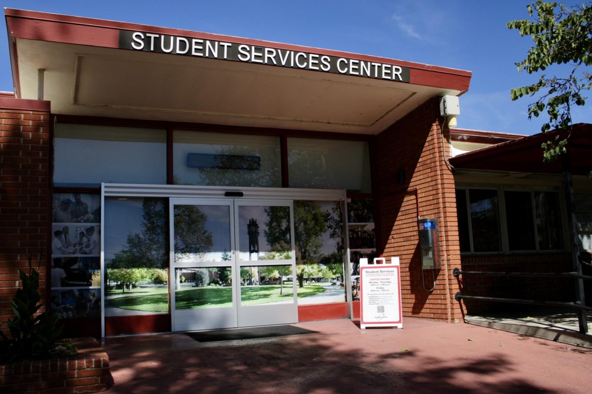 Entrance of Palomar College’s Student Services Center at the San Marcos campus, with glass doors and a sign outside under a clear blue sky.