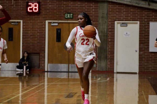 Kailani Flournoy has the basketball in her left hand and is looking for an open teammate to pass the ball to.