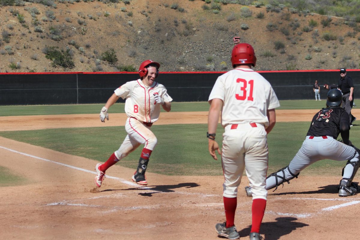 Outfielder Braedon Peterson-Cheek (#8) in a white and red jersey closes in on home base.