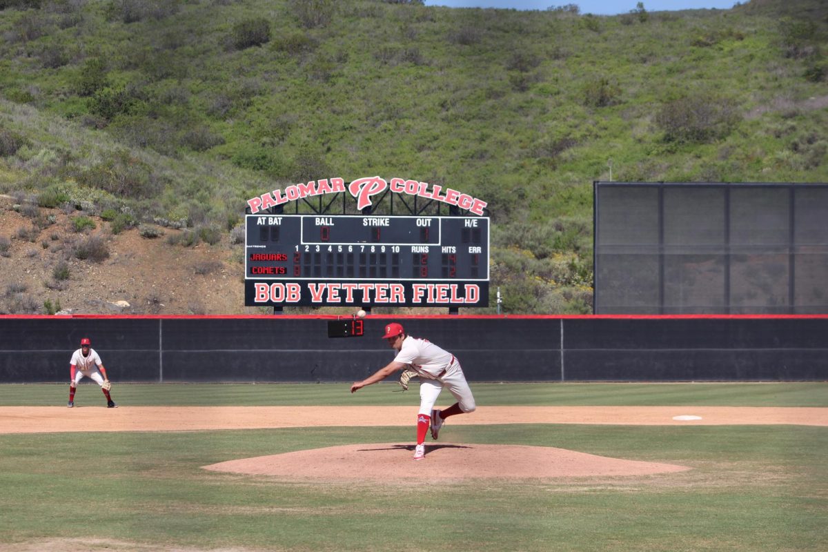 Ryan Herrod (#30) in a white and red uniform pitches the first inning, with the Palomar College Scoreboard appearing behind him.