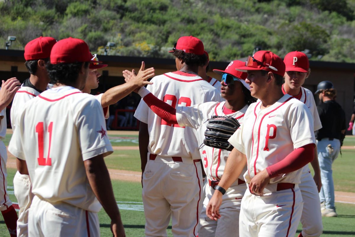 Justin Tucker (#3) of Palomar College high-fives a team member near the dugout after a strong inning.