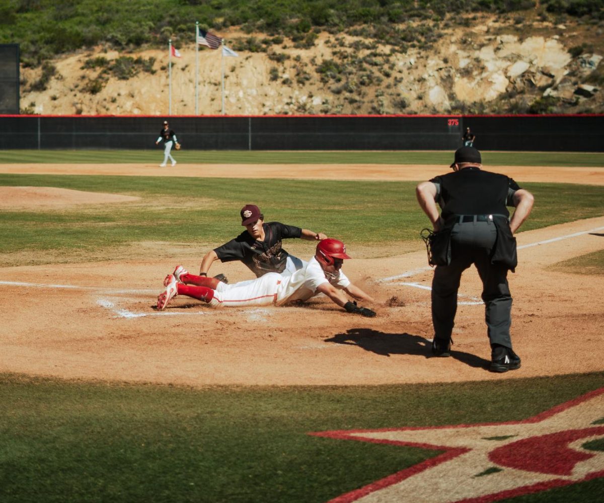 Palomar player Braedon Peterson-Cheek in white and red jersey sliding into home base.