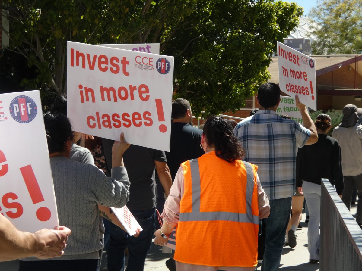 Attendees march holding signs that request more investment in classes on March, 12, 2026 alongside the Student Union at Palomar College. 