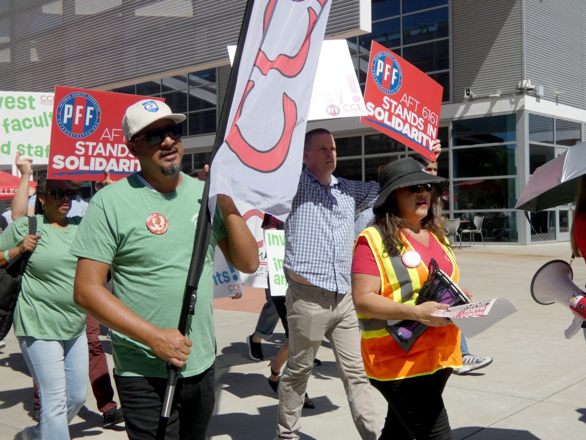 Carmelino Cruz (in green), Anel Gonzalez (in the safety vest), and Lawrence Lawson (in the plaid shirt) lead the march in solidarity for community college students and workers on March 12, 2026. 