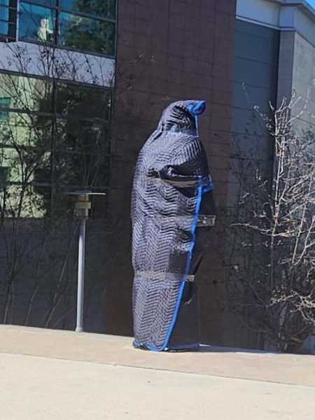the bronze statue covered in a black wrapping with blue edging