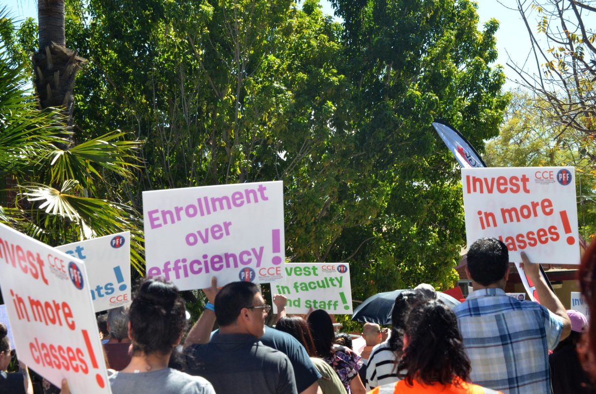 Protesters hold up signs while walking around campus during a rally on March 12, 2026 at the Palomar College San Marcos campus. 