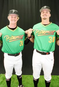 Two Palomar baseball players in Irish-green jerseys holding their hands to the Palomar logo.