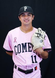Palomar baseball player in pepto-pink jersey holding a glove in left hand.