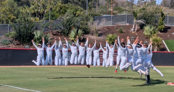 Palomar college softball players in all-white uniforms jump into the air.