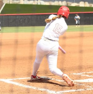 Palomar softball player Alexis Huey in a white jersey number 15 swings her bat at a pitch which resulted in a home run.