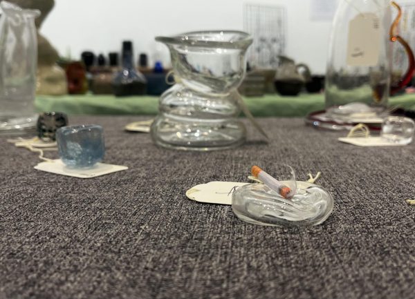 Glass ashtray with faux cigarette on Chase Lee's table.