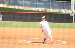 Palomar softball player Hailey White in a white uniform throws a pitch.