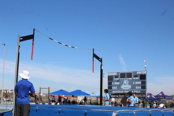 Judges in blue t-shirts stand around the pole vault landing area on the Mangrum track and field at Cal State San Marcos.