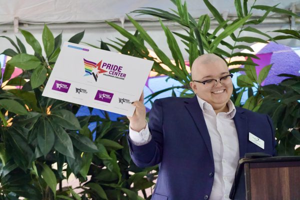 Lene Reynolds holds up a sign featuring the Pride Center's new logo: a star in rainbow colors.