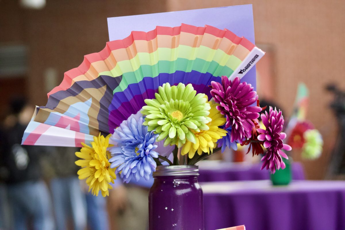 The centerpieces included different color flowers in a mason jar with a handheld fan with the pride flag design.