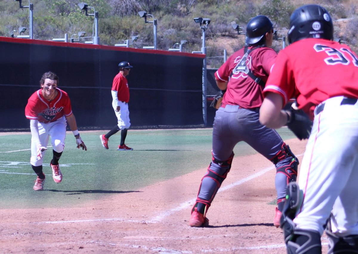 Palomar player runs and crouches forward as he prepares to slide into home plate.