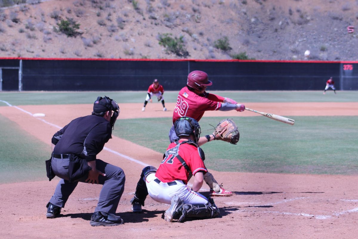 San Diego City batter in a maroon uniform swings and hits a pop fly towards center field.