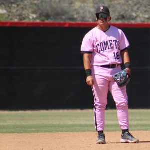 A Palomar baseball player in a pink uniform, number 18 stares to his right while standing near third base.