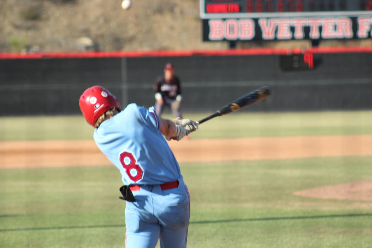 A baseball player in a light blue uniform and red helmet wearing number eight swings a bat.