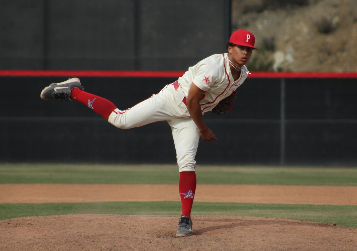 Comet baseball pitcher in a white uniform stands on his left leg after throwing a pitch.