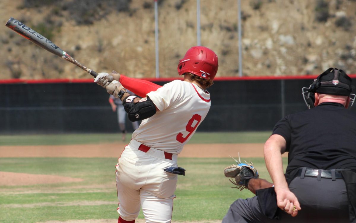 Palomar baseball player in a white uniform, number 9 swings at a pitch.