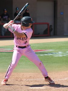 A Palomar baseball player in a pink uniform, number 2, prepares to swing his bat.