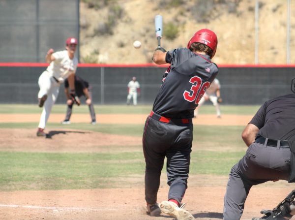 Palomar baseball player in a dark grey uniform, number 36, swings as the ball lines towards center field.
